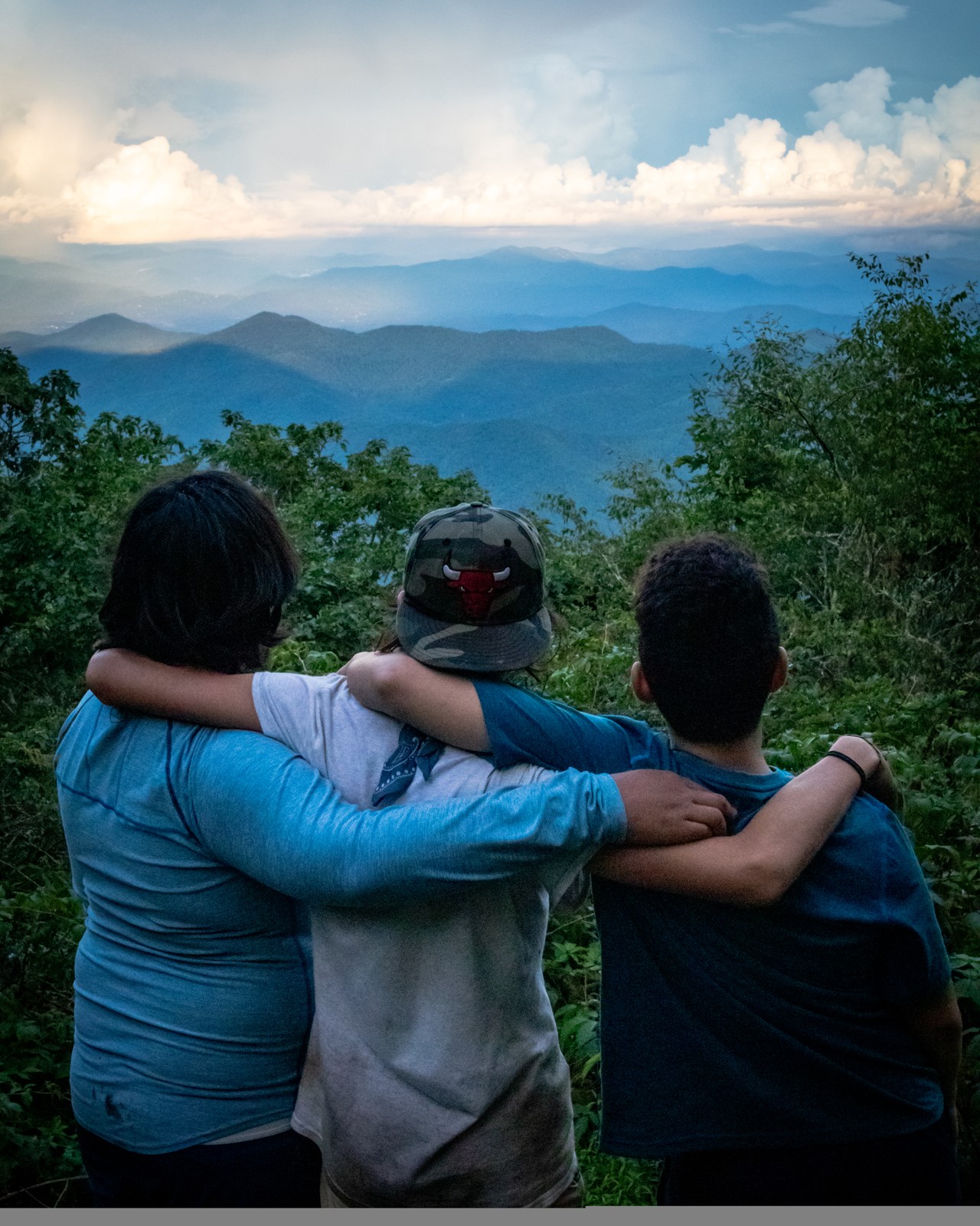 Three friends in their original everyday shirts sharing a mountain overlook